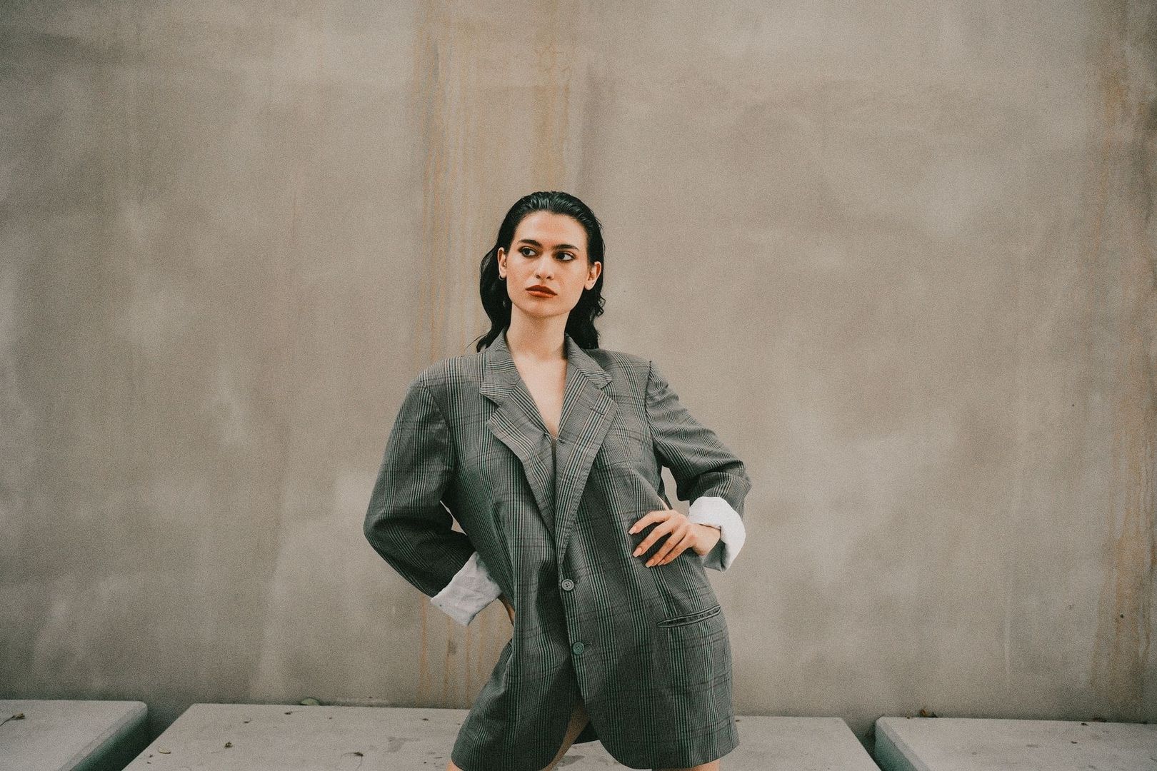 Person i oversized, randig blazer med markerad siluett mot neutral vägg
